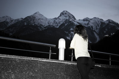 Rear view of woman standing on railing against mountain