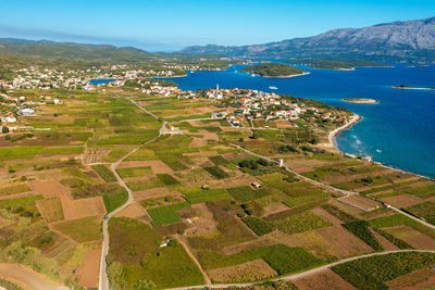 High angle view of agricultural field by sea against sky