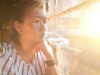 Close-up of thoughtful woman looking through bus window during sunset