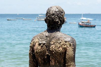 Rear view of man standing by sea against sky