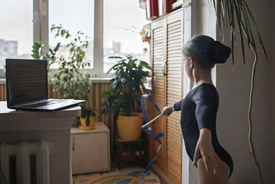 Side view of woman standing by window at home