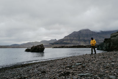 Man in yellow jacket walking on the shore in blábjörg iceland