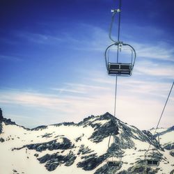 Low angle view of ski lifts at snowcapped mountains during sunset