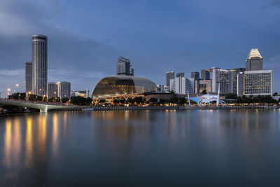 Buildings by lake in city at dusk