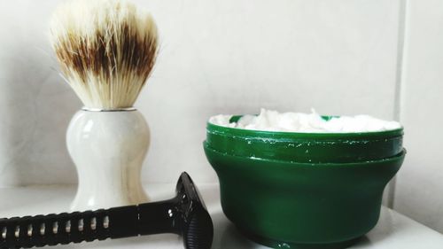 Close-up of shaving cream with brush on table at bathroom