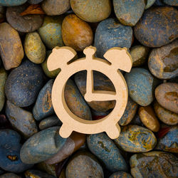 Close-up of wooden alarm clock on pebbles