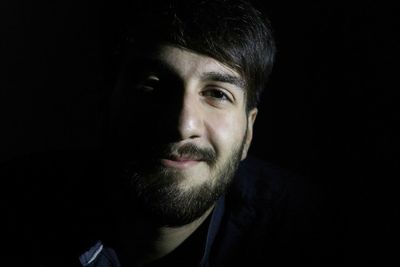 Portrait of young man against black background