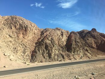 Rock formations by road against sky