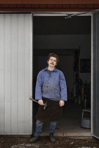 Blacksmith posing in front of his workshop