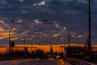 Cars on street against sky at sunset