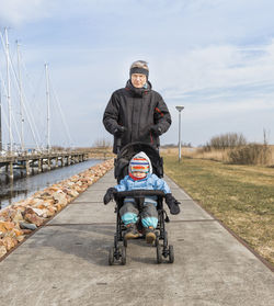 Grandfather pushing baby girl on stroller at sidewalk