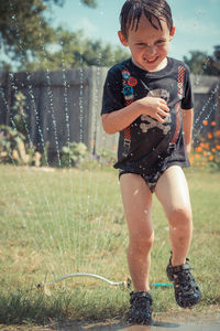 Full length of boy playing in sprinkler