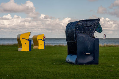 Lifeguard hut on field by sea against sky