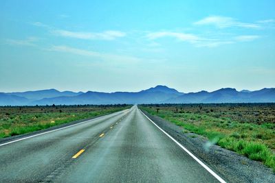 Road leading towards mountains against sky