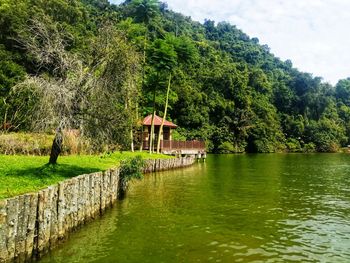 Scenic view of lake by trees and building against sky