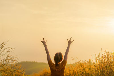 Rear view of woman standing by plants against sky