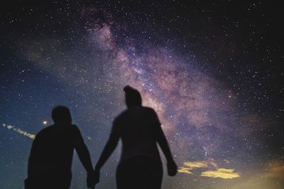 Silhouette friends standing against sky at night