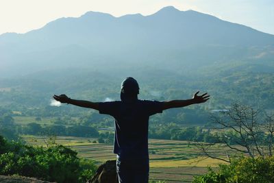 Man with arms outstretched standing on farm