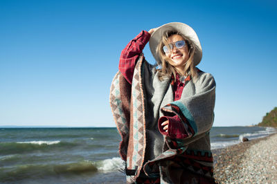 Woman standing at beach against clear blue sky