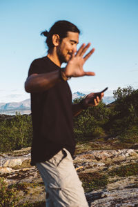 Side view of man standing on field against sky