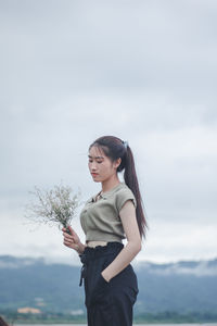 Young woman looking at camera against sky