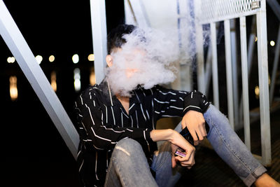 Man smoking cigarette while sitting outdoors