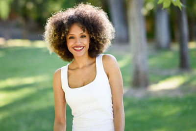 Portrait of smiling young woman against trees