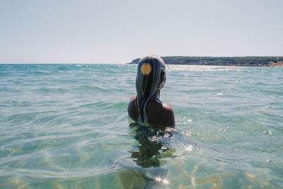 Man swimming in sea against clear sky