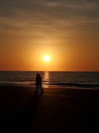 Silhouette woman on beach against sky during sunset