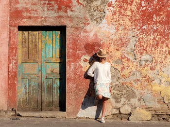 Full length of young woman posing by old house