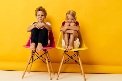 Portrait of sibling sitting on chair