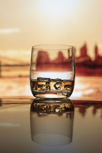 Close-up of drink on poolside against sky during sunset