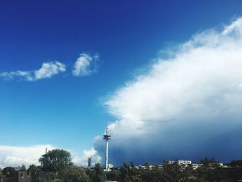 Low angle view of smoke emitting from factory against blue sky