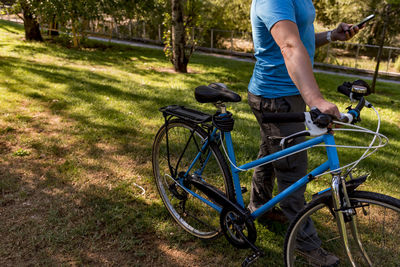 Unrecognizable man walking in the park with his bicycle