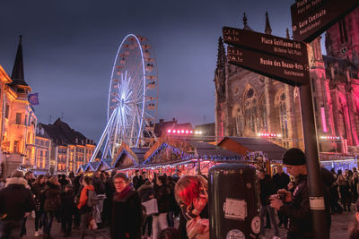 People in amusement park against sky in city