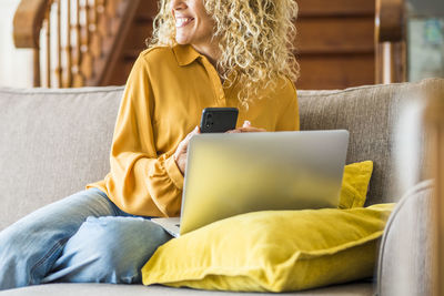 Woman using laptop while sitting on sofa at home