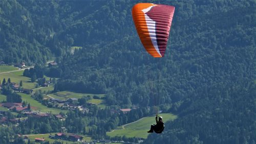 Person paragliding over landscape against sky