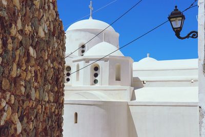 Stone wall and church against clear blue sky