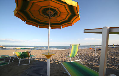 Chairs and tables on beach against clear sky