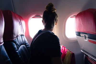 Woman looking through window while traveling in airplane