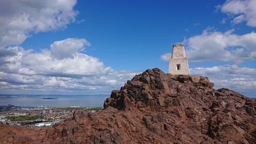 Low angle view of rock formation by building against sky