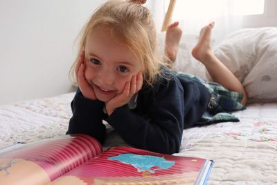 Portrait of a smiling girl lying on bed