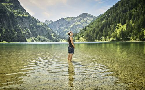 Mature woman standing knee deep in vilsalpsee while listening music on sunny day