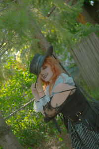 Portrait of young woman standing against trees