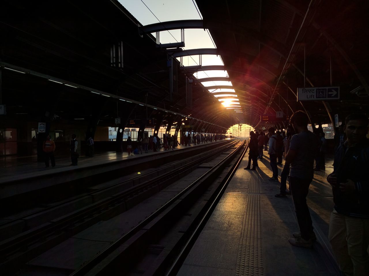 railroad track, transportation, rail transportation, railroad station platform, railroad station, public transportation, illuminated, the way forward, travel, men, train - vehicle, diminishing perspective, incidental people, text, vanishing point, journey, mode of transport, railway station, passenger