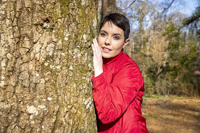 The young woman is hugging a large oak tree. 