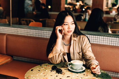 Portrait of young woman sitting at restaurant table