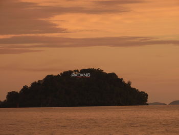 Distant view of text on island against sky during sunset