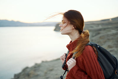 Woman standing by sea against sky