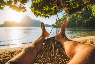 Man relaxing on shore by sea against sky